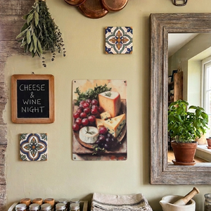 Vintage style metal wall art hanging on a kitchen wall with an image on it of a cheeseboard with cheeses selection & buncges of grapes & herbs