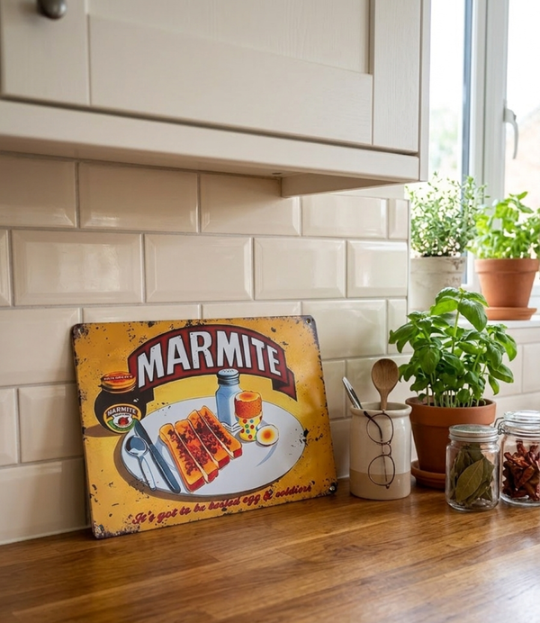 Vintage style Marmite sign on a kitchen counter leaning against the tiled wall below the kitchen units