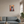 Vintage style metal sign hanging on a living-room wall above a sofa with a picture on it of a Border Collie in a sitting pose