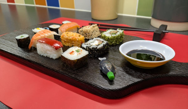 YAKISUGI WHALE STYLE ASH SERVING BOARD displaying a selection of sushi & dipping bowl of soy sauce