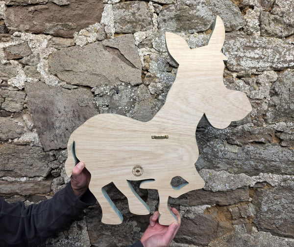 reverse side of wooden donkey wall art being held up for sizing