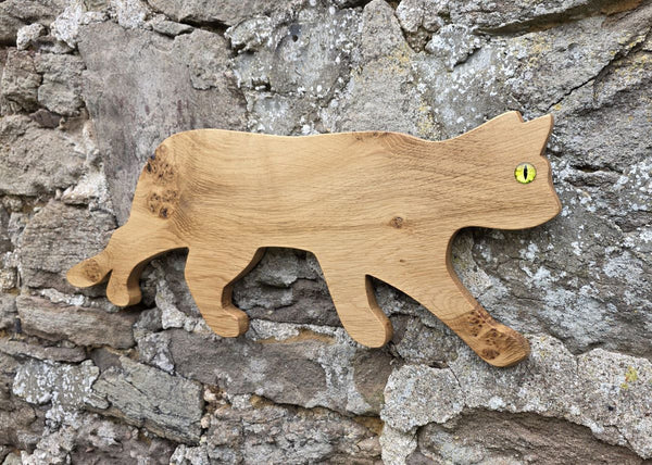 Stalking cat wooden wall art viewed at an angle on a stone wall