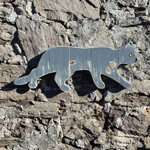 Stalking cat wooden wall art displayed on a stone wall