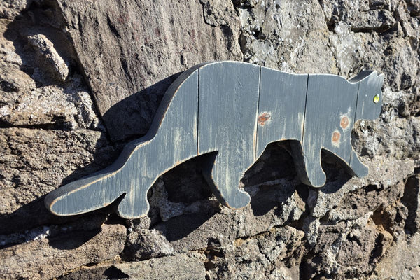 Stalking cat rustic wooden wall art displayed on a stone wall and viewed at an angle