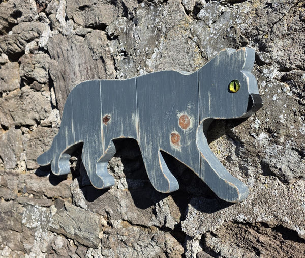 Stalking cat wooden wall art displayed on a stone wall viewed at an angle