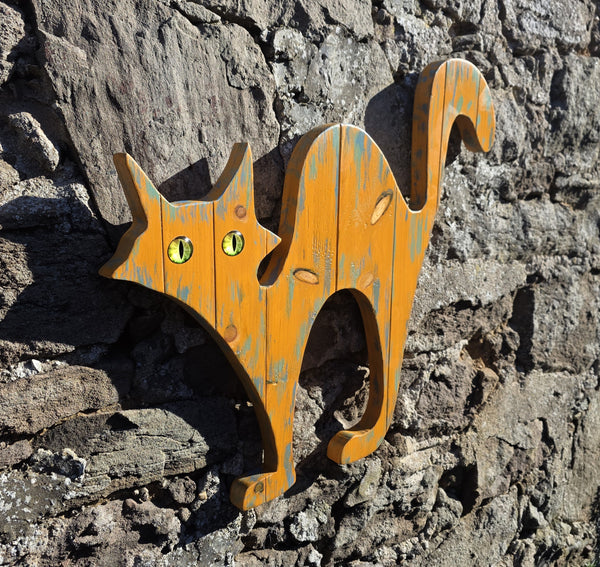 alley cat wooden wall art hanging on a stone wall side view