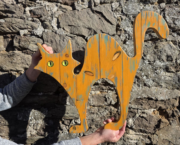 alley cat wooden wall art being held against stone wall background