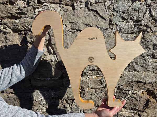 reverse side of alley cat wooden wall art being held against stone wall background