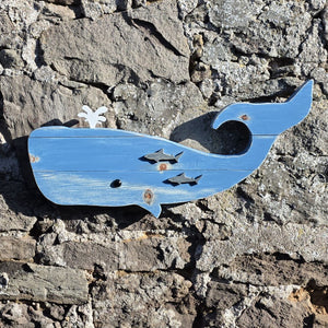 Wooden whale wall art displayed on a stone wall