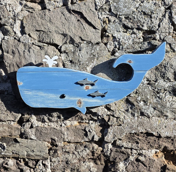Wooden whale wall art displayed on a stone wall