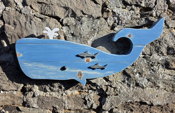 Wooden whale wall art displayed on a stone wall close up view