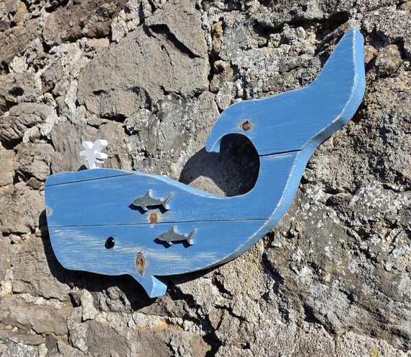 Blue whale rustic wooden wall art displayed on a stone wall viewed at an angle