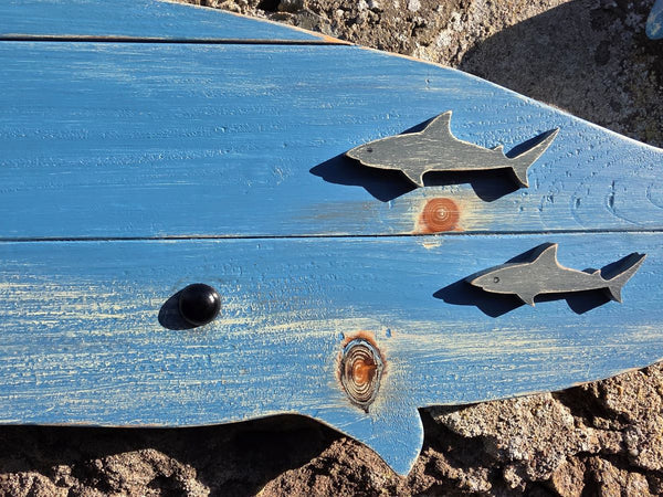Close up view of two small plywood pilot sharks on the surface of the blue whale wooden wall art