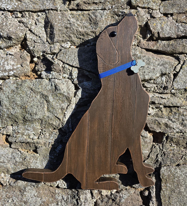 Wooden Labrador Retriever wearing a blue decorative collar  wall art against a stone wall