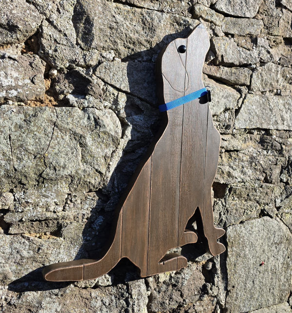 Side view of Wooden Labrador Retriever wearing a blue decorative collar wall art against a stone wall