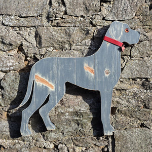 Wooden Great Dane dog with a red collar against a stone wall