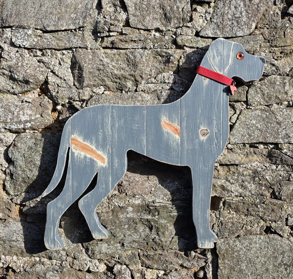 Wooden Great Dane dog with a red collar against a stone wall