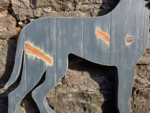 Wooden Great Dane dog with a red collar against a stone wall, close up view