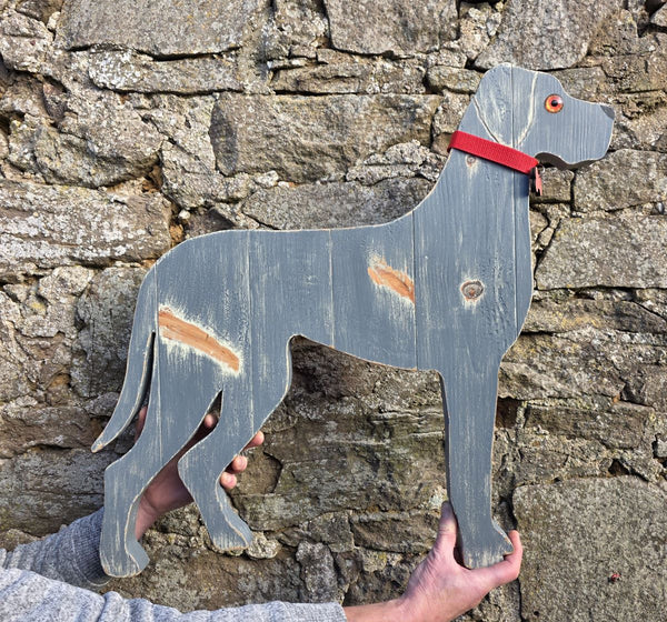 Wooden dog wall art held against a stone wall