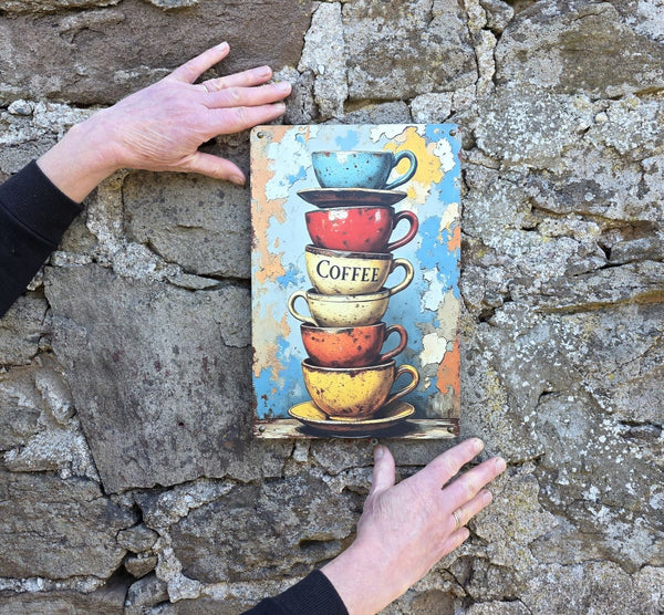 Decorative sign with stacked coffee cups on a stone wall being held up to show its sizing