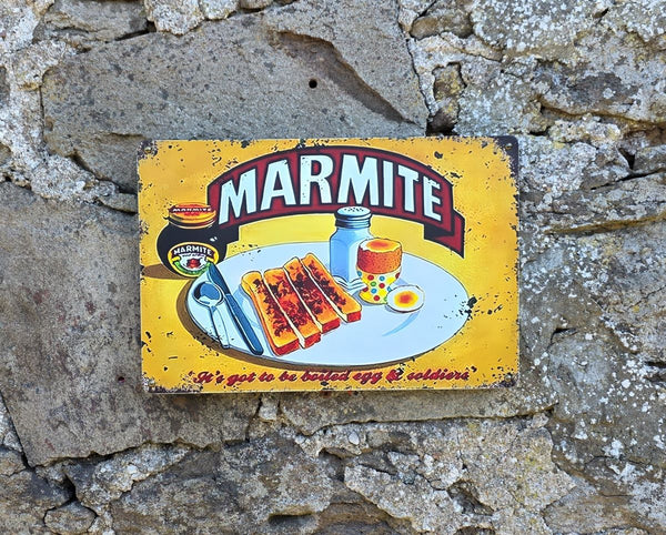 Vintage-style metal sign with Marmite image on it, hanging on a stone wall