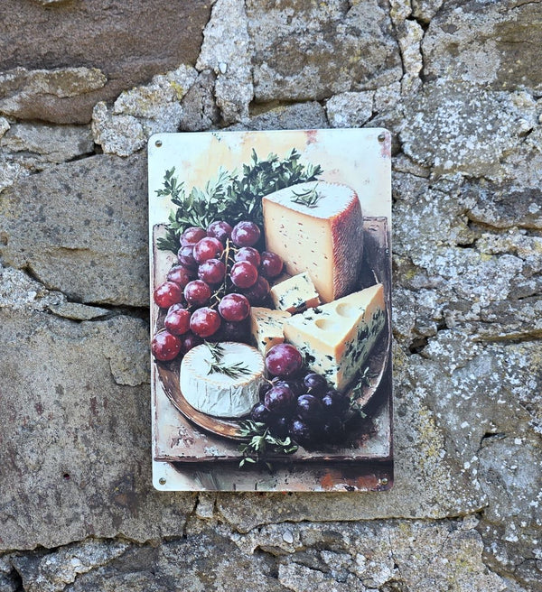 Decorative vintage style metal sign (repro) hanging on a stone wall with an image of cheeses and grapes on a cheeseboard