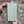 The reverse-side of a Vintage style shabby chic, sage green pine wall art shutter being held up against an old stone wall