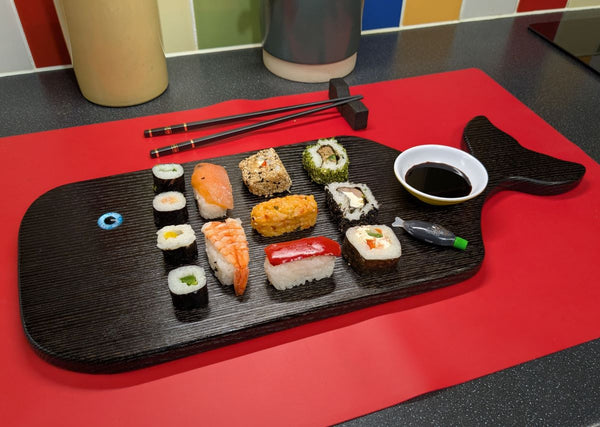 YAKISUGI WHALE STYLE ASH SERVING BOARD displayed with Sushi in a kitchen setting alongside a pair of Chopsticks & a Yakisugi oak chopstick rest