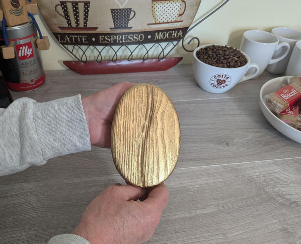 Gold coffee bean (small size) wall art decor up close showing Yakisugi style Ash wood being held for sizing