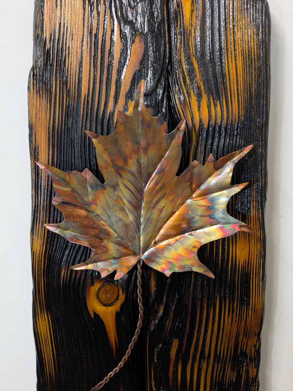 Douglas Fir & flame painted copper maple leaf wall art display piece hanging on a wall very close up view of copper leaf