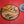Ash wood 'Coffee Bean style' serving board displayed with croissant, butter, jam & funky red butter knife along side a cup of coffee overhead view