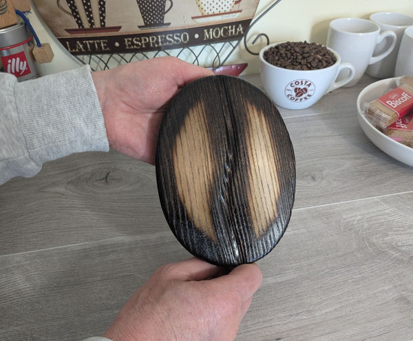 Medium ash wood coffee bean being held to show sizing