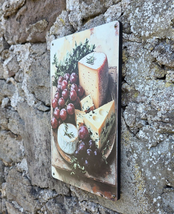 Another side view of a decorative vintage style metal sign (repro) hanging on a stone wall with an image of cheeses and grapes on a cheeseboard