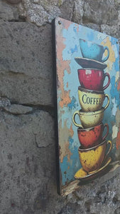 Video clip of a repro vintage style metal sign with a colourful image of a stack of  six coffee cups, against a stone wall